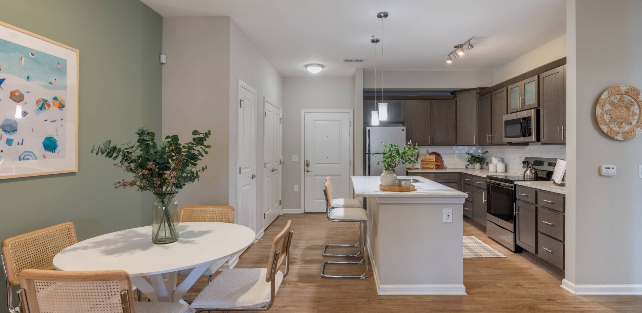 Hawthorne at Leland open kitchen with stainless steel appliances, a large island with bar seating, and a round dining table with modern chairs.