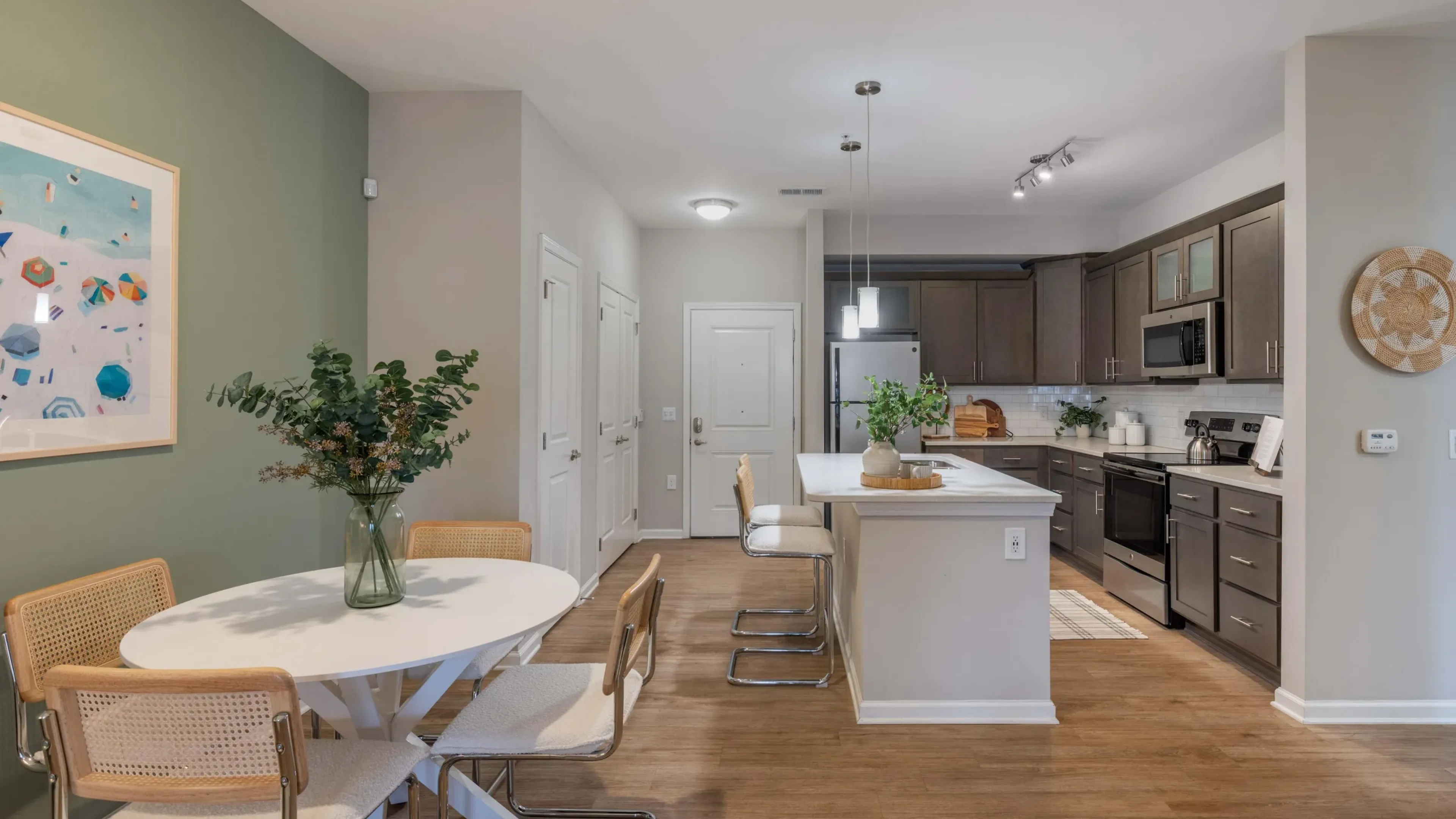 Hawthorne at Leland apartment interior dining area and kitchen with a dining table and chairs, kitchen island, and floor-to-ceiling cabinets