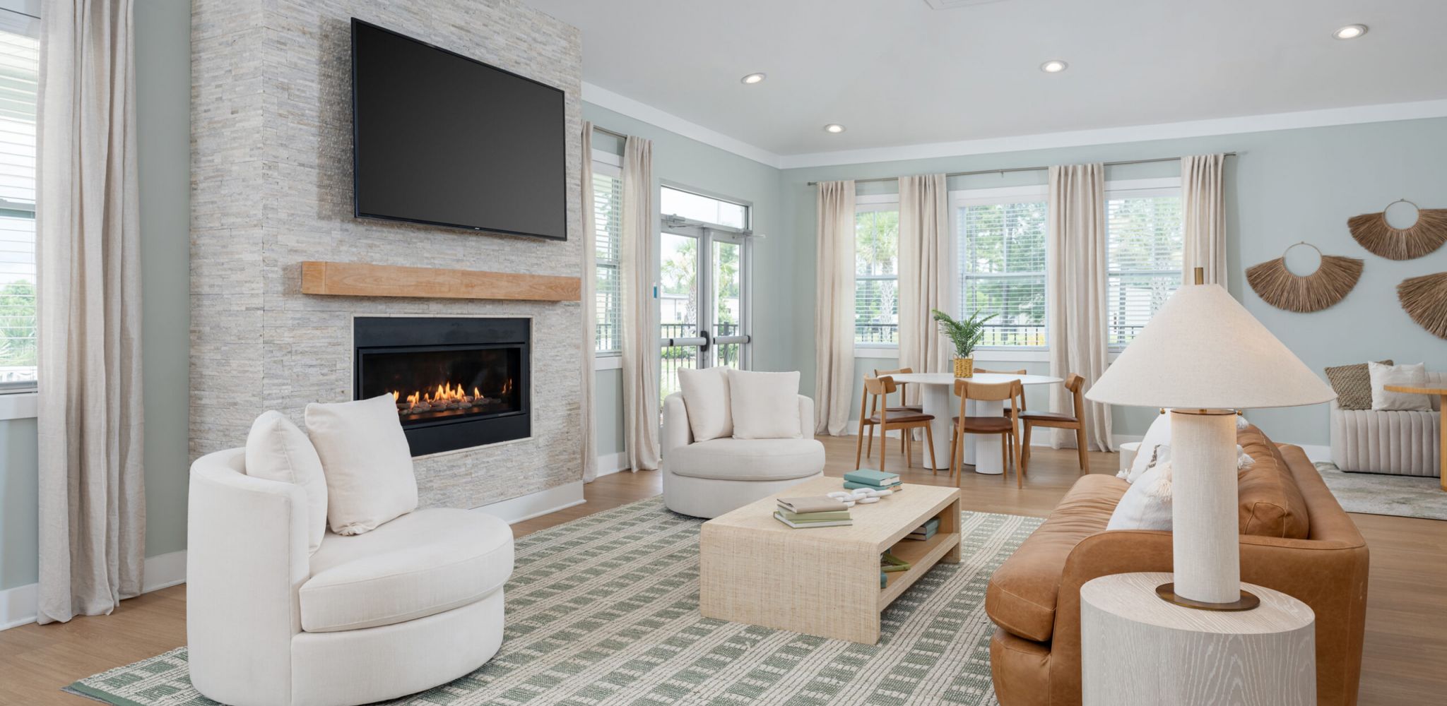 Hawthorne at Leland cozy nook with a white sectional sofa and a wooden dining table beneath decorative woven wall art.